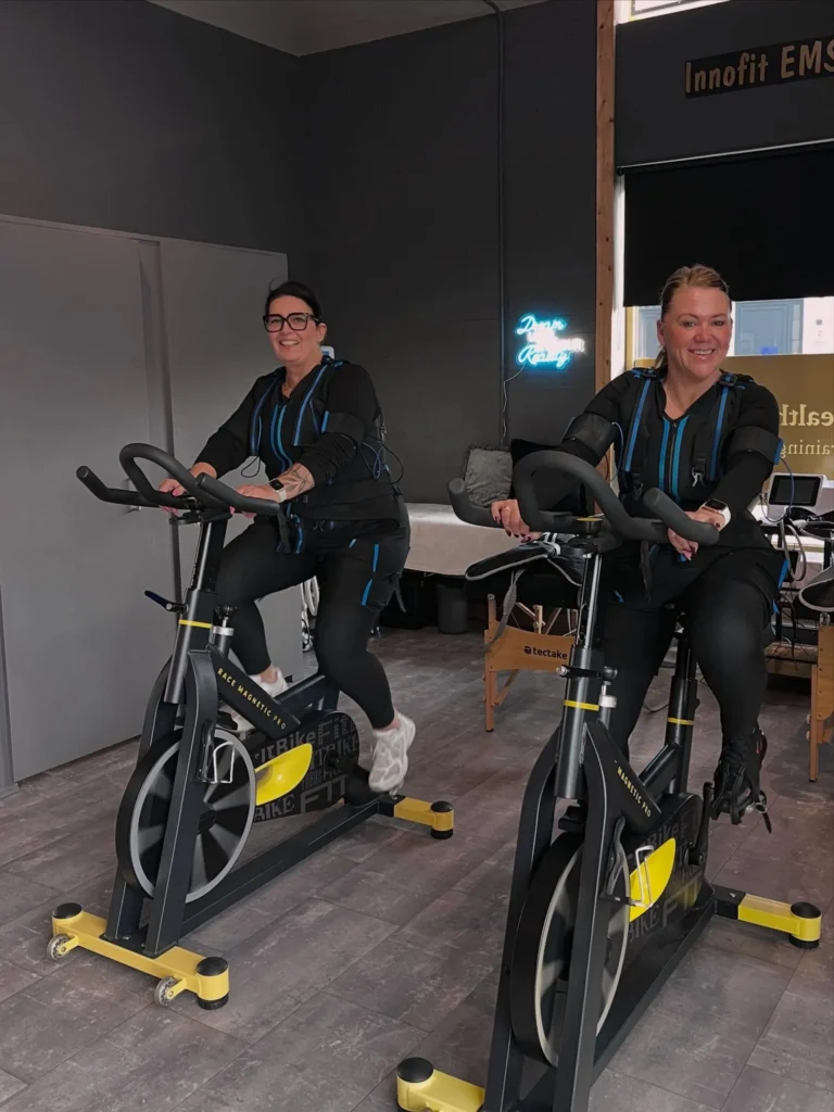 Twee klanten fietsen in een EMS-pak in de studio van Innofit
